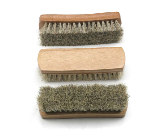 The Cathcart Elliot *seconds* 3x-shoe-polishing-brush set includes three vertically arranged wooden brushes with horse hair bristles: the top with light, the middle slightly coarser, and the bottom thickest. The handles are made of light wood.