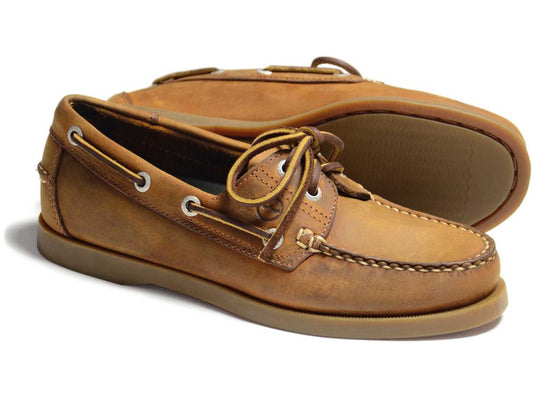 The Orca Bay CREEK Ladies Deck Shoe in Sand Nubuck features brown leather, visible stitching, laces, rubber soles, metal eyelets, and a slip-resistant sole pattern with one shoe displayed on its side.