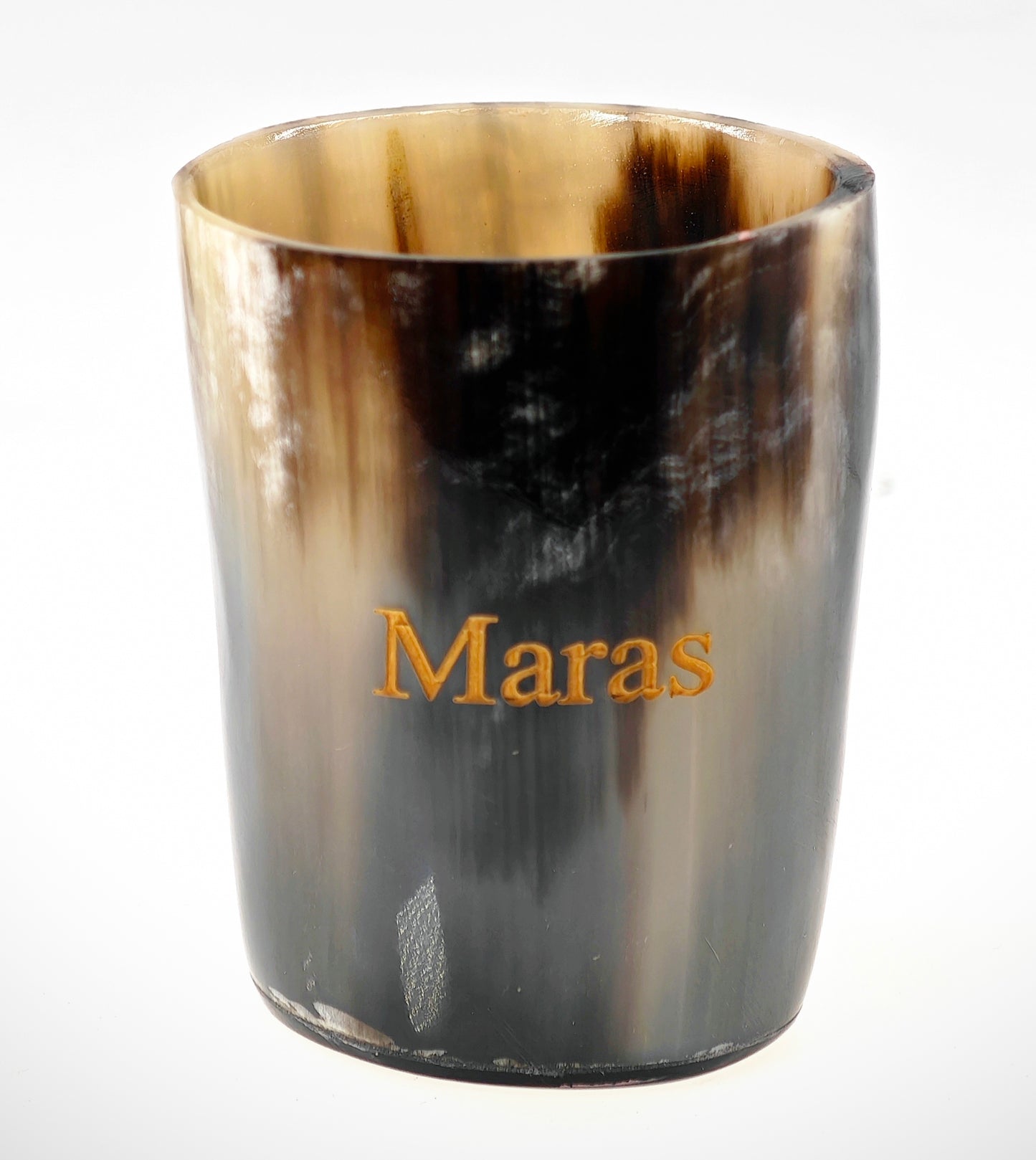 A close-up of the Cathcart Elliot Personalised Real Horn Cup Shot Glass showcases its smooth, glossy surface with a Viking style. It features Maras engraved in gold and displays natural color variations from dark brown to beige, resembling polished wood or horn.