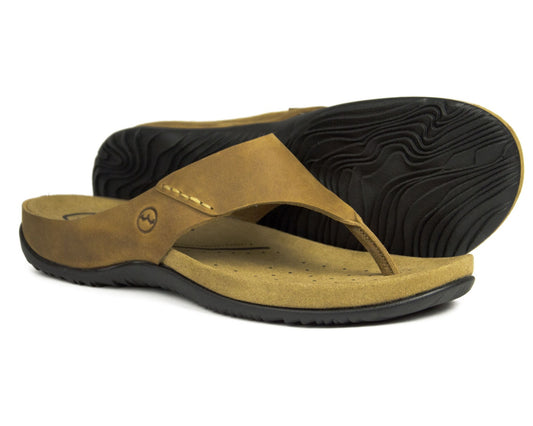 Orca Bays BORA mens leather flip-flops feature a oiled leather design with black rubber soles. One sandal displays a smooth insole and stitched strap, while the other reveals a textured sole with a wavy pattern.