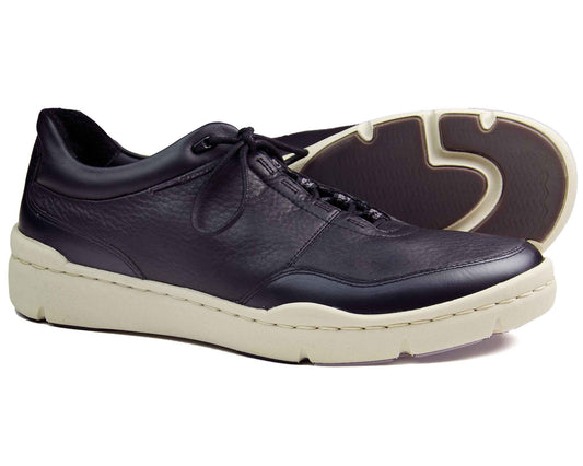 The Orca Bay SALE CAMDEN Mens Black Sneakers feature a stylish design with thick white soles. One sneaker stands upright, displaying its sleek design and laces, while the other tilts to showcase its textured sole and detailed stitching.