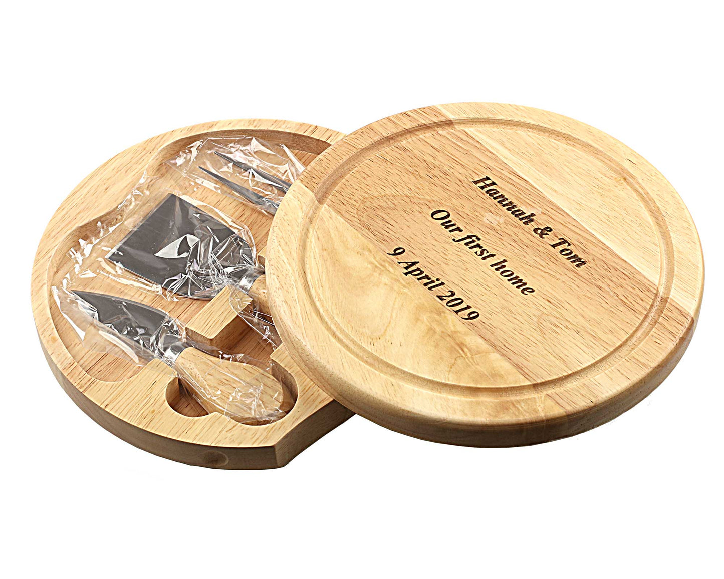 The Cathcart Elliot *SECONDS* personalisable 19cm round cheeseboard gift set, engraved with Hannah & Tom, Our First Home, 9 April 2019, opens to reveal three cheese tools: a fork, knife, and chisel.