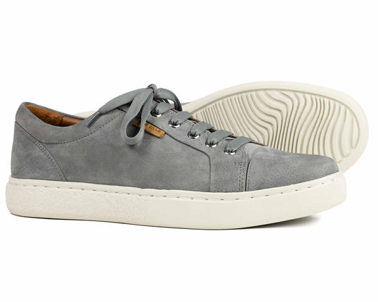 Orca Bays Kensington Mens Grey Sneakers feature a pair with white soles. One stands upright, showcasing its lightweight design and gray laces; the other lies on its side, revealing the shock-absorbing insole and wavy tread pattern.