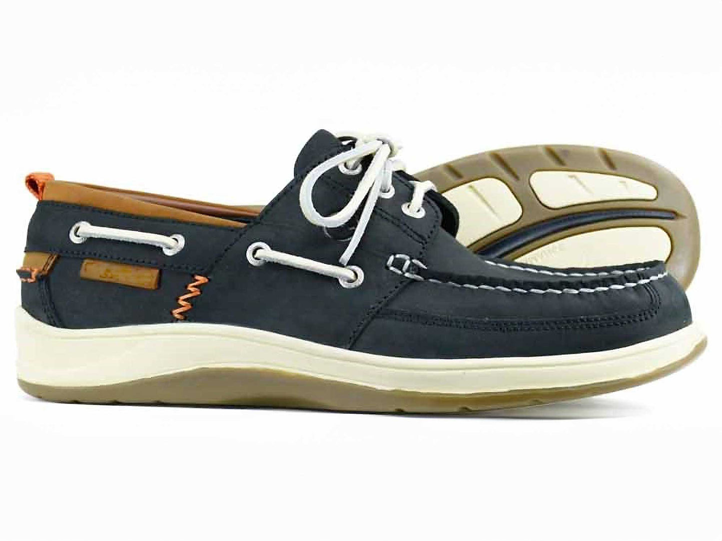 The OCEAN Mens Black Waterproof Deck Shoe by Orca Bay features premium black oiled nubuck, white laces and stitching, a non-slip tan and white sole with orange detailing at the heel. One shoe stands upright while the other is on its side, revealing the soles design.