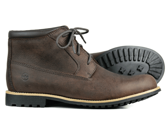 The SALE TETBURY ladies dark brown ankle boot by Orca Bay is made from soft leather, featuring black rubber soles and laces, ideal for autumn. One boot stands upright while the other lies on its side, highlighting the detailed tread pattern.